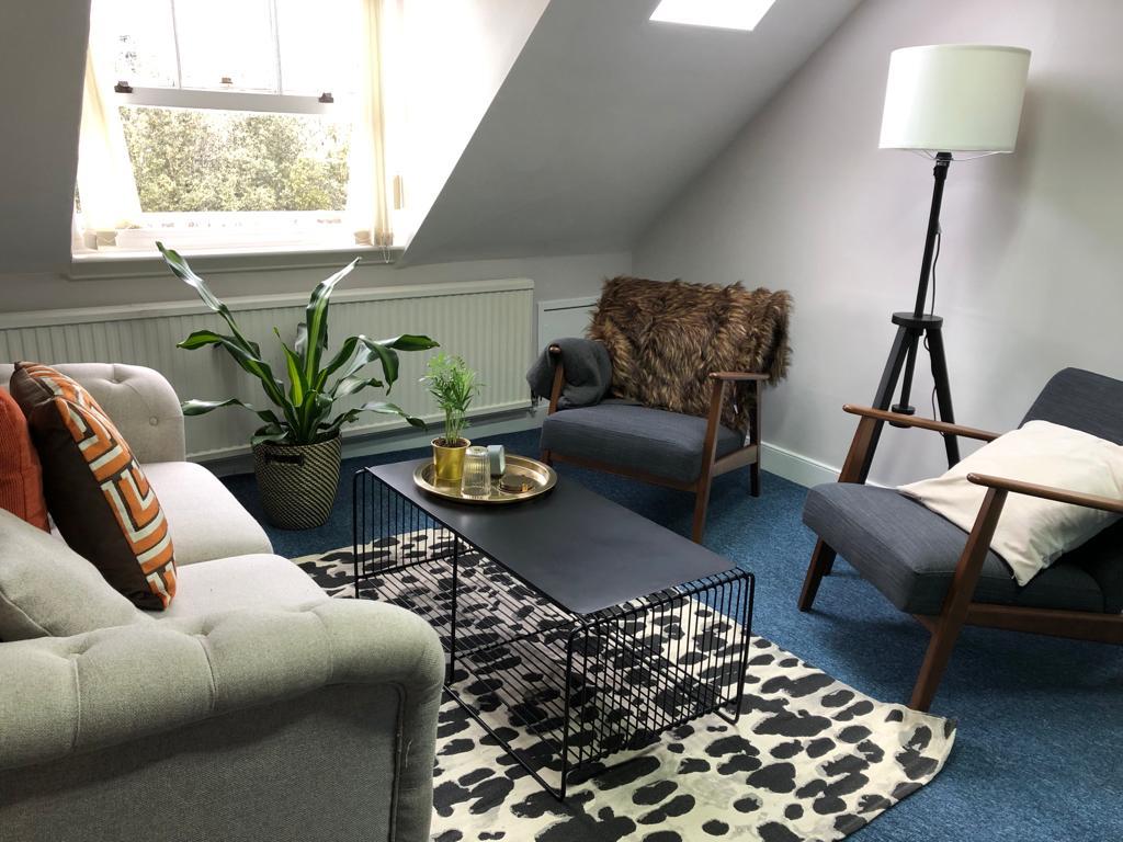 Photo or a room with two dark chairs, and a window.